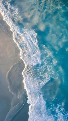 an aerial view of the ocean with waves coming in