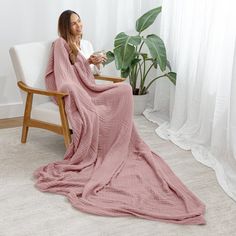 a woman sitting in a chair with a pink blanket