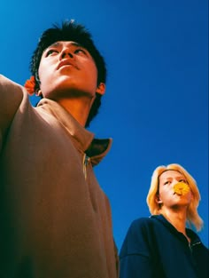 two people standing next to each other looking up at the sky with their eyes closed