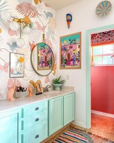 a bathroom with colorful wallpaper and artwork on the walls, along with two sinks