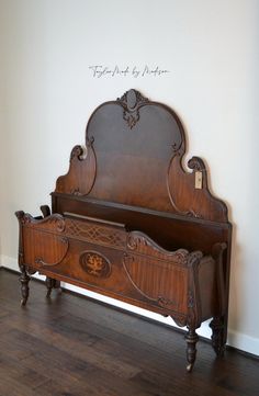 an antique wooden bed frame with intricate carvings on the headboard and foot board, against a white wall