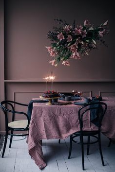 the table is set for two with candles and flowers hanging from the chandelier