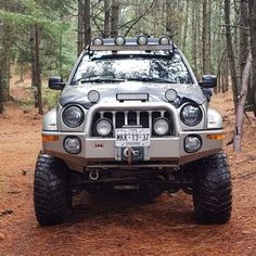 a jeep is parked in the woods with its lights on and it's front bumper up