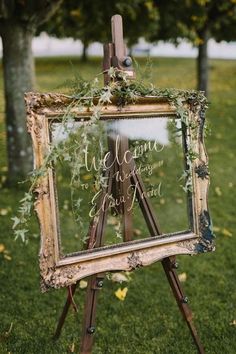 an easel with greenery on it and a sign that says welcome to the wedding