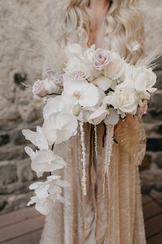 a woman in a dress holding a bouquet of white flowers and feathers on her head