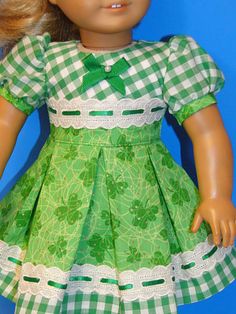 the doll is wearing a green dress with white laces on it's waist