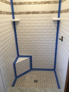 a white shower with blue tape on the walls and floor in a tiled bathroom area