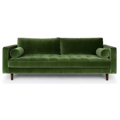 a green velvet couch with two pillows on it's back and arms, facing away from the camera