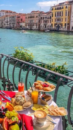 a table full of food and drinks on a balcony overlooking the water in venice, italy