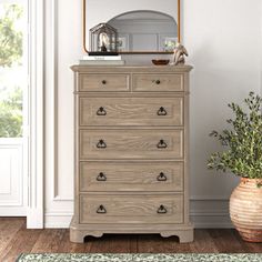 a wooden dresser sitting next to a mirror on top of a white wall in a room