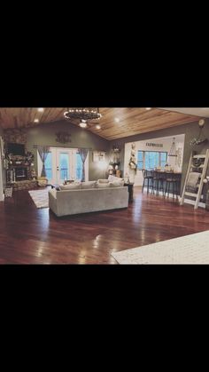 a living room with hard wood flooring and white furniture in the middle of it