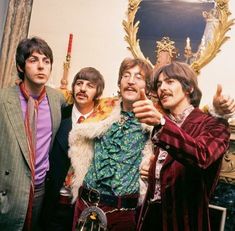 the beatles posing for a photo in front of a mirror with one hand up to his face