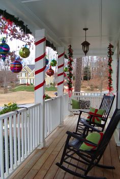 a porch with rocking chairs and christmas decorations hanging from the ceiling on it's front porch