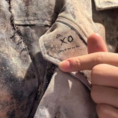 someone is holding up a piece of clothing with the word xo written on it