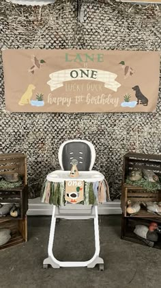 a baby highchair sitting in front of a birthday banner and other items on display