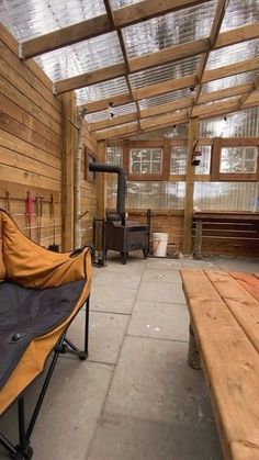 an outdoor area with wooden walls, benches and a wood burning stove in the background