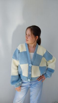 a woman standing in front of a wall wearing a blue and white striped cardigan