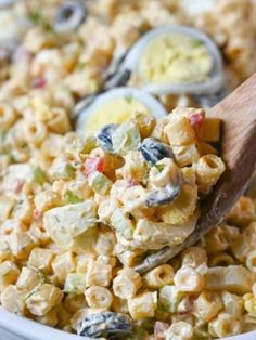 a wooden spoon in a bowl filled with macaroni salad