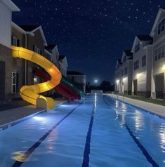 an empty swimming pool at night with water slide