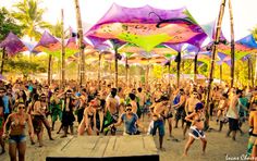 a group of people standing around each other in front of umbrellas at a festival