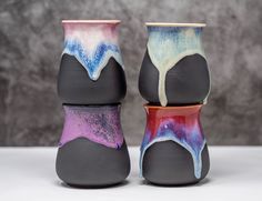 two black vases with different colored designs on them