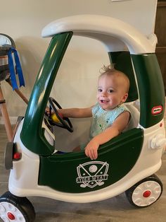 a small child in a green and white toy car