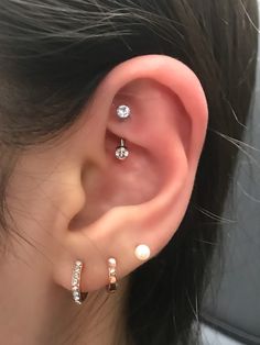 a woman wearing three different types of ear piercings