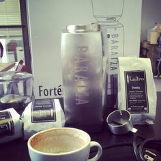 a cup of coffee sitting on top of a table next to a blender and other items