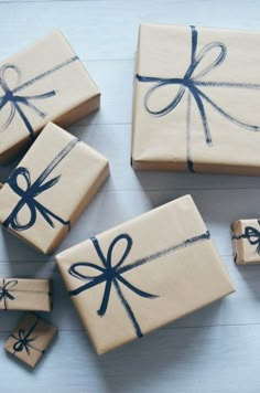 four wrapped presents with blue bows on them sitting on a white table next to each other