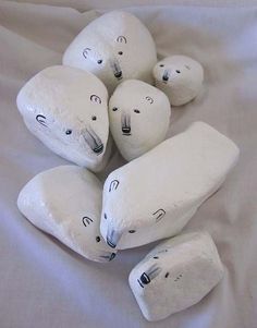 five stuffed polar bears sitting on top of a white bed sheet with eyes drawn on them