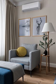 a living room with a bed, chair and paintings on the wall above it's headboard