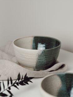 two bowls sitting next to each other on top of a white tablecloth covered table