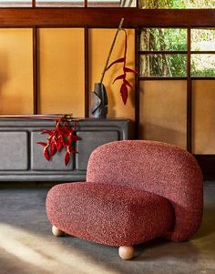 a red chair sitting next to a plant in a room