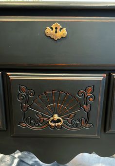 an old dresser has been painted black with gold trim and ornate designs on the drawers