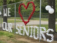 a fence decorated with red and white paper mache letters that spell out save the date