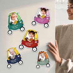 a woman standing next to a wall with stickers on it that have pictures of children in cars