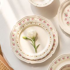 a white table topped with plates and bowls filled with flowers on top of each plate