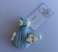 a blue and white brooch with a baby in it's diaper next to a tag