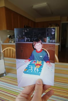 a person holding up a card with a photo of a boy sitting at a table