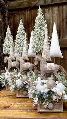 christmas trees and ornaments are on display in front of a wooden wall with an old - fashioned sleigh