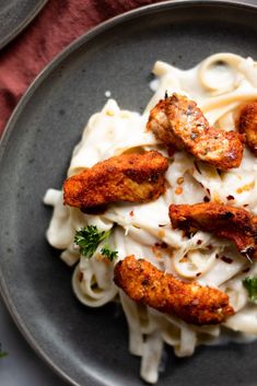 a plate of pasta with chicken wings and parmesan sauce on it, ready to be eaten