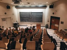 an empty lecture hall with people sitting at tables and chairs in front of the chalkboard