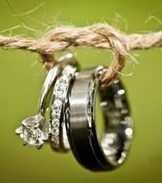 three wedding rings hanging from a rope with two diamonds on them and one diamond in the middle