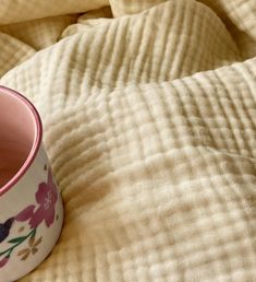 a pink cup sitting on top of a bed