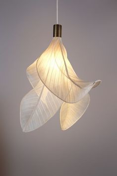 a white light hanging from a ceiling with two leaves attached to the lightshade