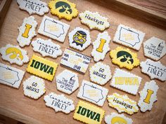 decorated cookies are arranged on a wooden tray with words and symbols in the shape of iowa