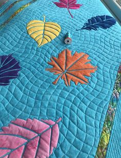 a quilted table runner with colorful leaves on it