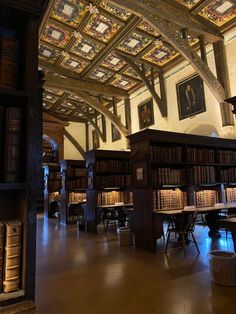 an old library with many bookshelves and paintings on the ceiling, along with two tables