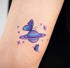 a small tattoo on the arm of a woman with butterflies around her neck and an object in the shape of a saturn