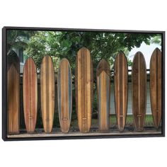 a group of surfboards mounted to the side of a wooden wall with trees in the background